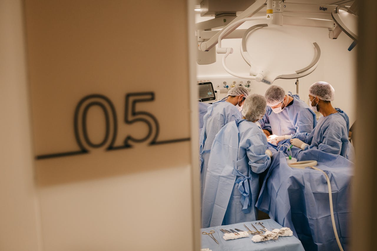 A group of surgeons operates in a hospital's sterile environment, focusing on a complex procedure.